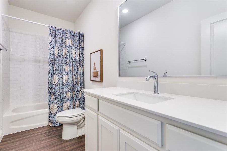 Full bathroom with vanity, toilet, shower / tub combo, and hardwood / wood-style floors