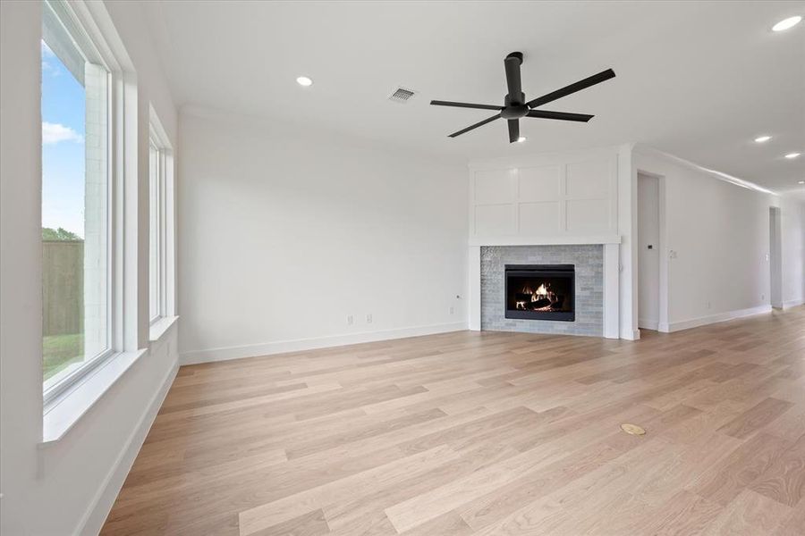 Unfurnished living room featuring a fireplace, ceiling fan, and light wood-type flooring