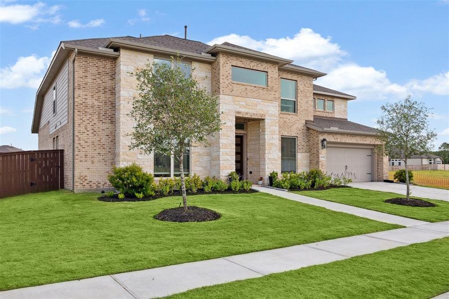 This view of the front elevation across the front lawn, shows the combination brick and stone exterior surface.