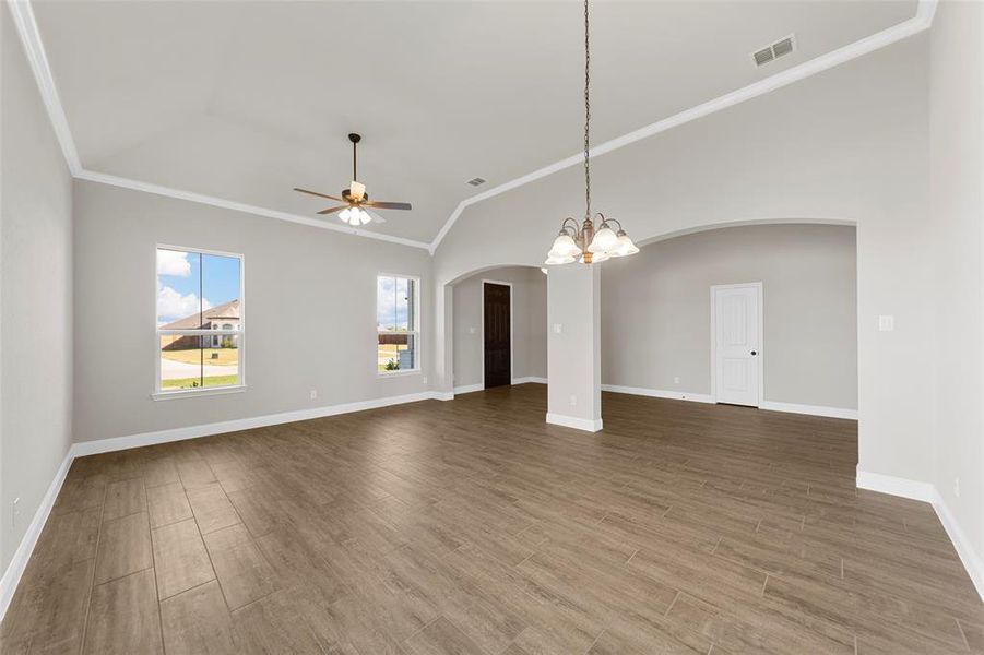 Unfurnished room featuring crown molding, vaulted ceiling, ceiling fan with notable chandelier, and hardwood / wood-style floors