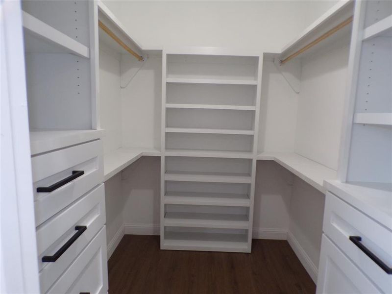 Walk in closet with dark hardwood / wood-style flooring