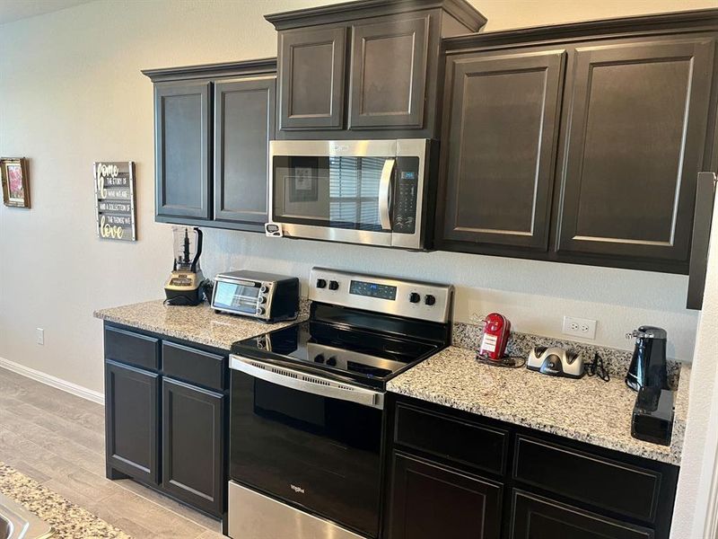 Kitchen featuring light wood-type flooring, stainless steel appliances, and light stone counters