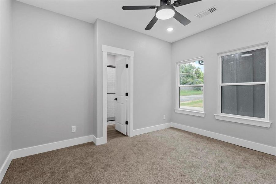 Unfurnished bedroom featuring ensuite bathroom, carpet, and ceiling fan