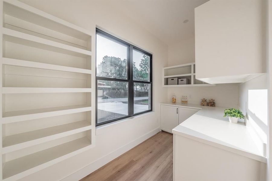 Butler's Pantry featuring white cabinetry, and  blonde plank, wood-like luxury vinyl floors.