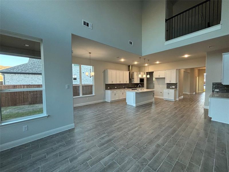 Kitchen featuring white cabinets, an island with sink, dark hardwood / wood-style floors, a high ceiling, and pendant lighting