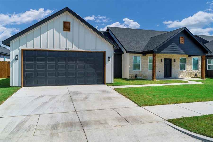 View of front of property featuring a front yard and a garage