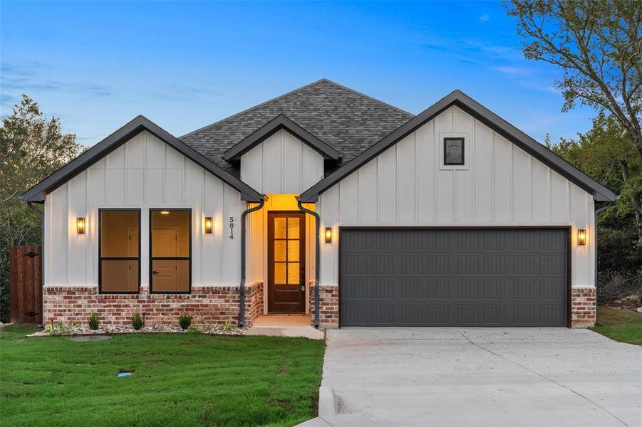 Modern inspired farmhouse featuring a front lawn and a garage