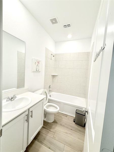 Full bathroom with toilet, vanity, hardwood / wood-style floors, and tiled shower / bath