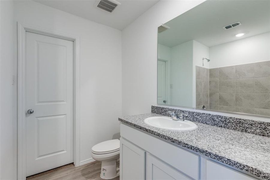 Bathroom featuring a shower, hardwood / wood-style floors, vanity, and toilet