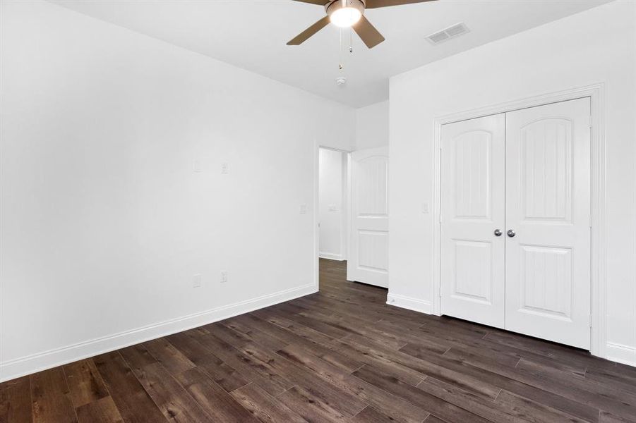 Unfurnished bedroom featuring dark wood-type flooring, a closet, and ceiling fan