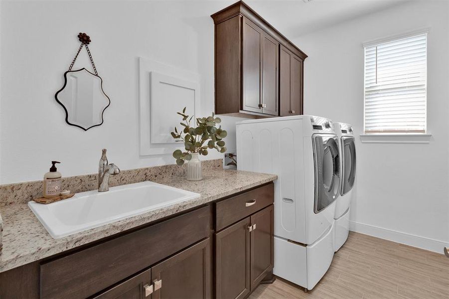 Spacious laundry room with lower cabinets and upper cabinets and large oversized sink.