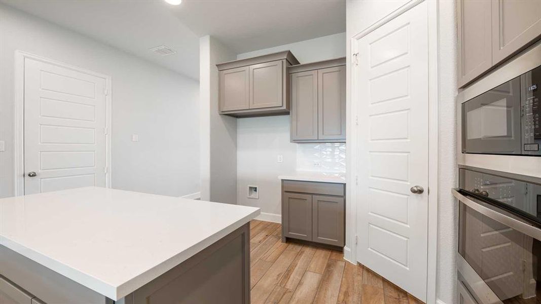 Kitchen featuring appliances with stainless steel finishes, light hardwood / wood-style flooring, a kitchen island, and gray cabinetry