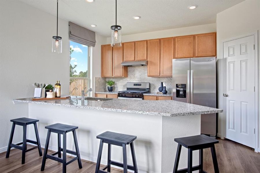 This stunning kitchen displays such a beautiful the beautiful pendant lighting over the granite countertop that is extended for a breakfast bar.  Additional features include stained cabinets, custom neutral paint, light modern backsplash, SS appliances, recessed lighting, high ceilings, large window and walk in pantry!