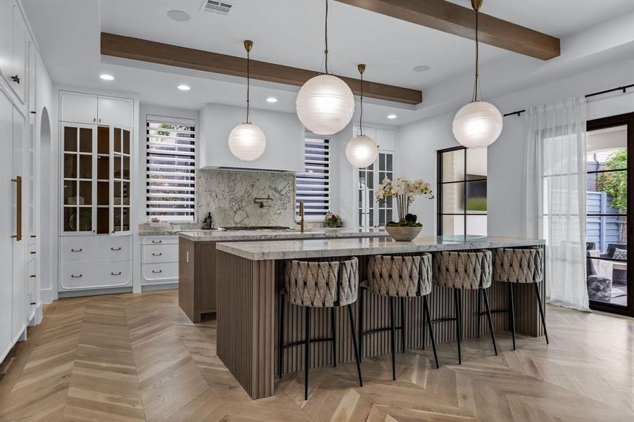 Kitchen featuring pendant lighting, a large island, light parquet floors, and white cabinetry