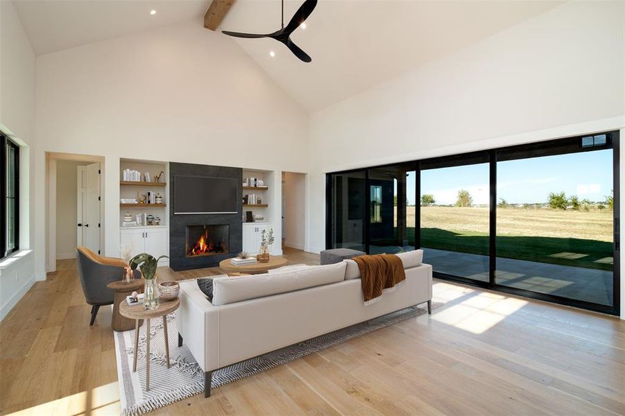 Virtually staged living room with ceiling fan, high vaulted ceiling, beamed ceiling, and light hardwood / wood-style flooring