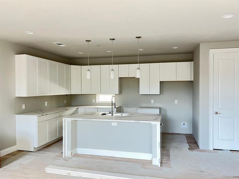 Kitchen with light hardwood / wood-style flooring, white cabinets, a kitchen island with sink, pendant lighting, and sink