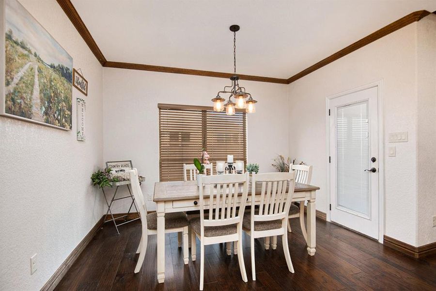 Dining space with an inviting chandelier, dark hardwood / wood-style floors, and crown molding