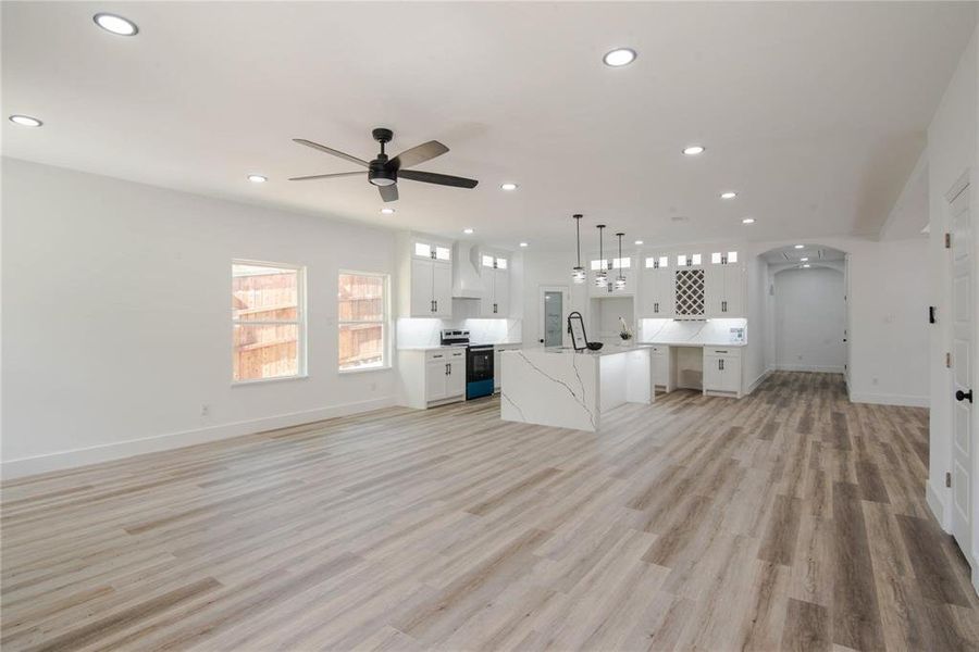 Unfurnished living room featuring light wood-type flooring, ceiling fan, and sink