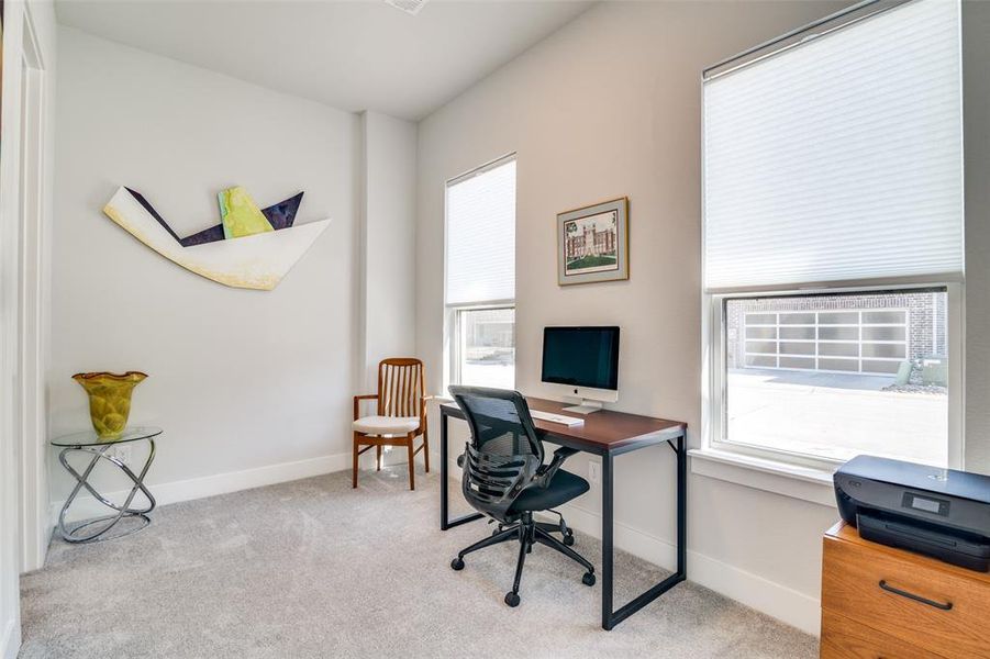 The first room off the foyer is a spacious study with light color carpeting and large windows with top-down, bottom up blinds.