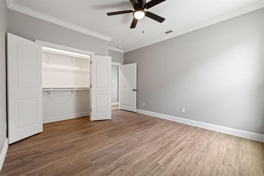 Bedroom featuring wood-type flooring, ornamental molding, ceiling fan, and a closet
