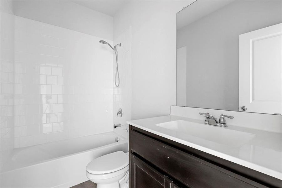 Full bathroom with toilet, tiled shower / bath combo, and vanity