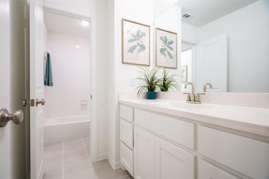 Bathroom featuring vanity, tiled shower / bath combo, and tile patterned floors