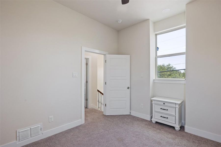Upstairs bedroom with ceiling fan and light colored carpet