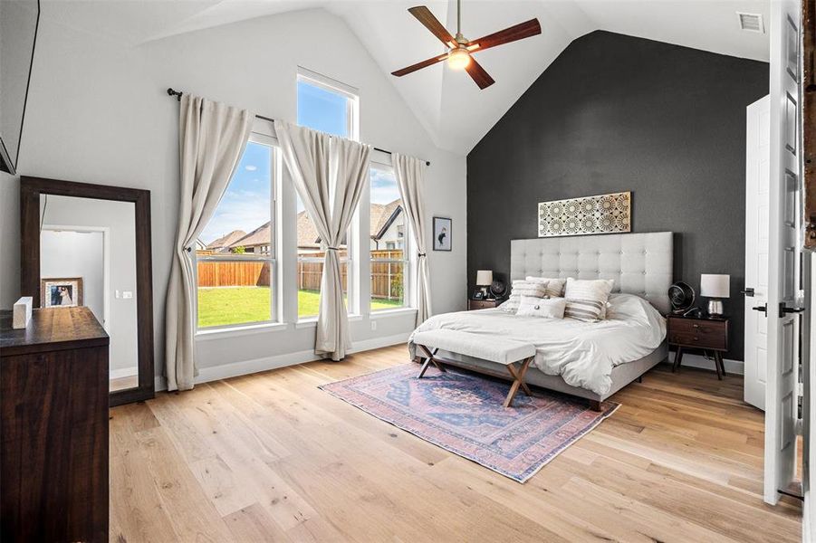 Bedroom with light hardwood / wood-style floors, high vaulted ceiling, and ceiling fan