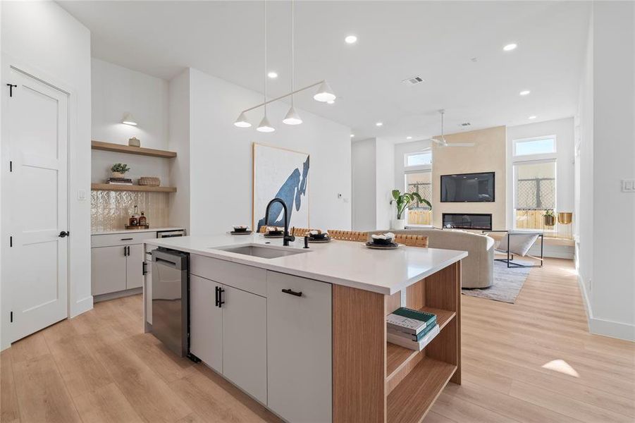 This spacious kitchen island doubles as a perfect gathering spot, providing ample room for meal preparation and casual dining. The natural wood accents add warmth, while the open shelving offers both style and convenience. Flowing effortlessly into the living area, the layout is designed for easy entertaining and a seamless transition between cooking, dining, and relaxation.