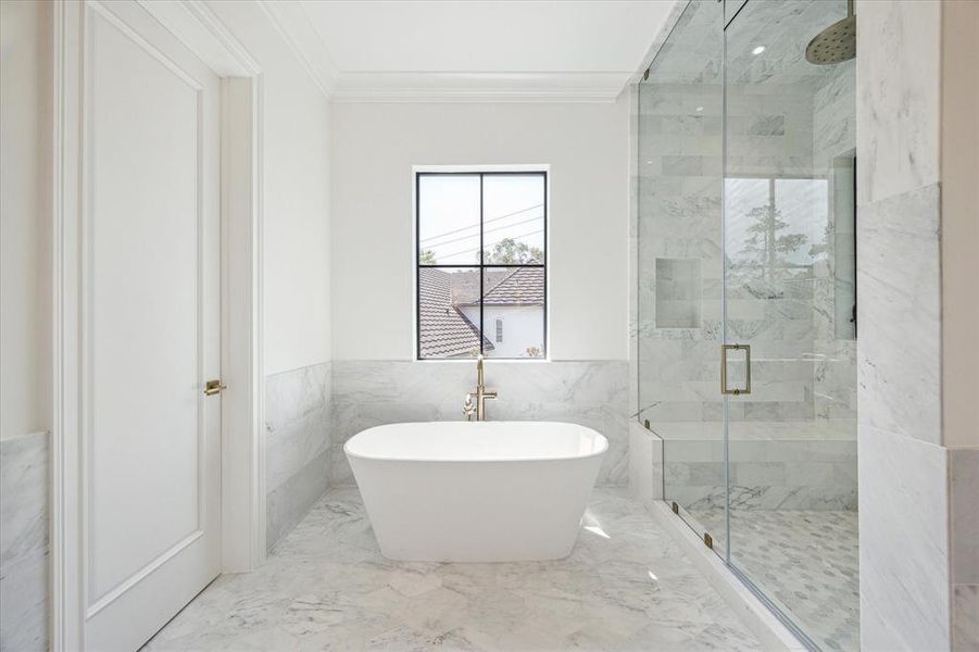 Indulge in luxury in this marble-clad primary bathroom, complete with a beautiful soaking tub perfect for unwinding after a long day. The walk-in shower and vanity with ample knee space provide convenience, while the tree-top views create a serene and tranquil atmosphere.