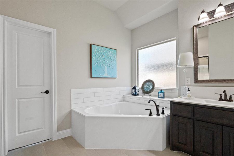 Bathroom featuring vanity, a bath, and tile floors