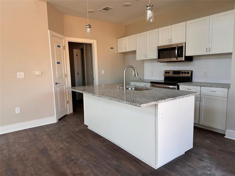 Kitchen featuring an island with sink, stainless steel appliances, dark hardwood / wood-style floors, and sink