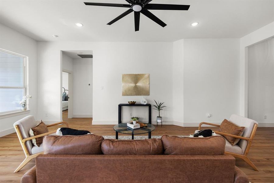 Living room with ceiling fan and light hardwood / wood-style flooring