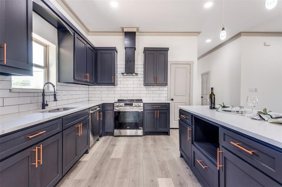 Kitchen featuring stainless steel appliances, crown molding, sink, light hardwood / wood-style floors, and backsplash