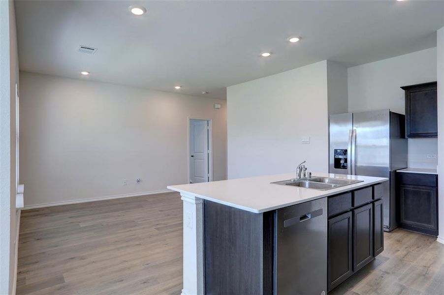 Kitchen with light hardwood / wood-style flooring, stainless steel appliances, a center island with sink, and sink