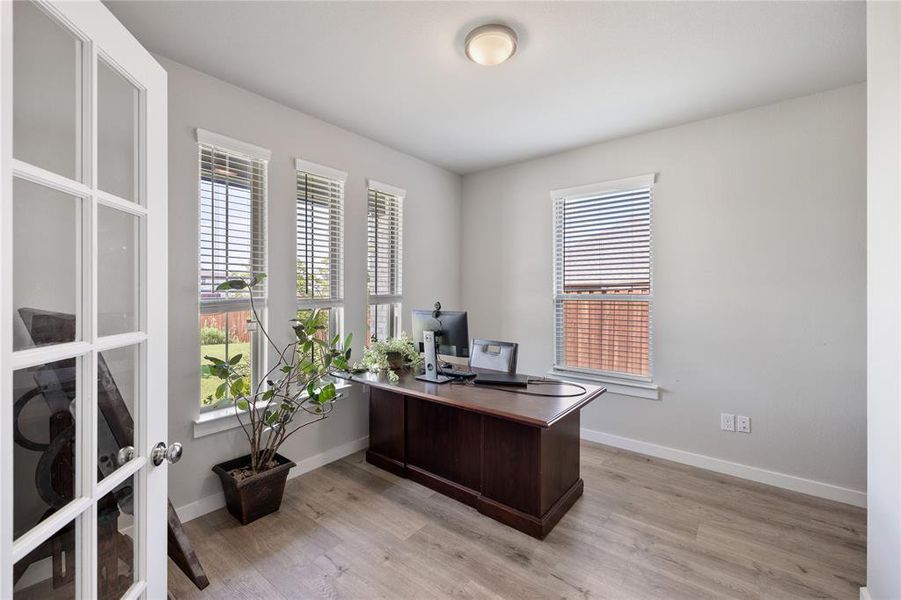 Office space with a healthy amount of sunlight, french doors, and light wood-type flooring