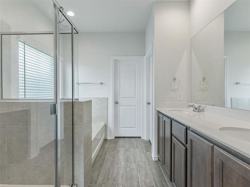 Bathroom with double vanity, plus walk in shower, and hardwood / wood-style floors