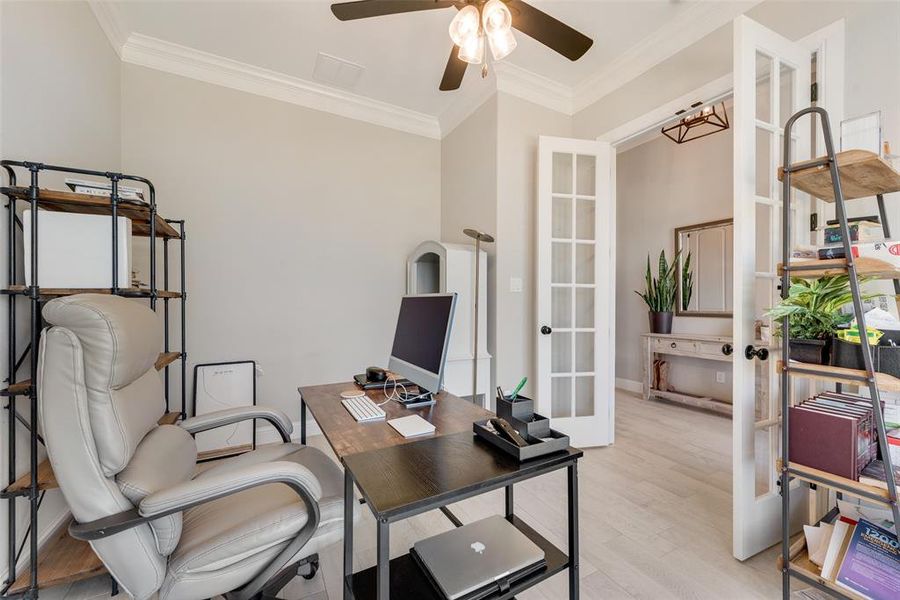 Office space with light hardwood / wood-style floors, ornamental molding, ceiling fan, and french doors