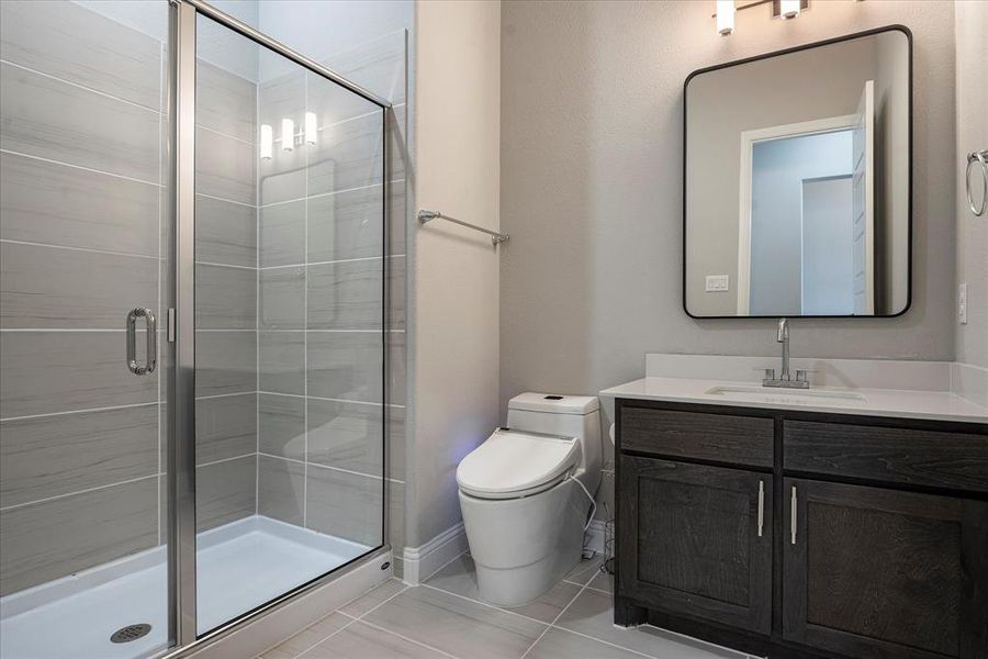 Bathroom featuring vanity, tile patterned floors, walk in shower, and toilet