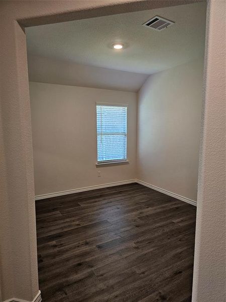 Empty room with vaulted ceiling and dark hardwood / wood-style flooring