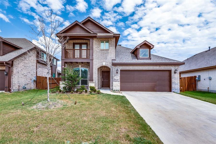 View of front of home with a front yard, a garage, and a balcony