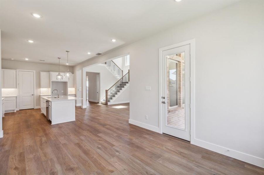 Kitchen featuring a kitchen island with sink, light hardwood / wood-style flooring, sink, pendant lighting, and white cabinetry