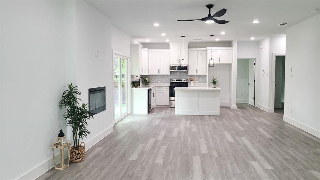 Kitchen featuring light wood-type flooring, white cabinetry, ceiling fan, and stainless steel appliances