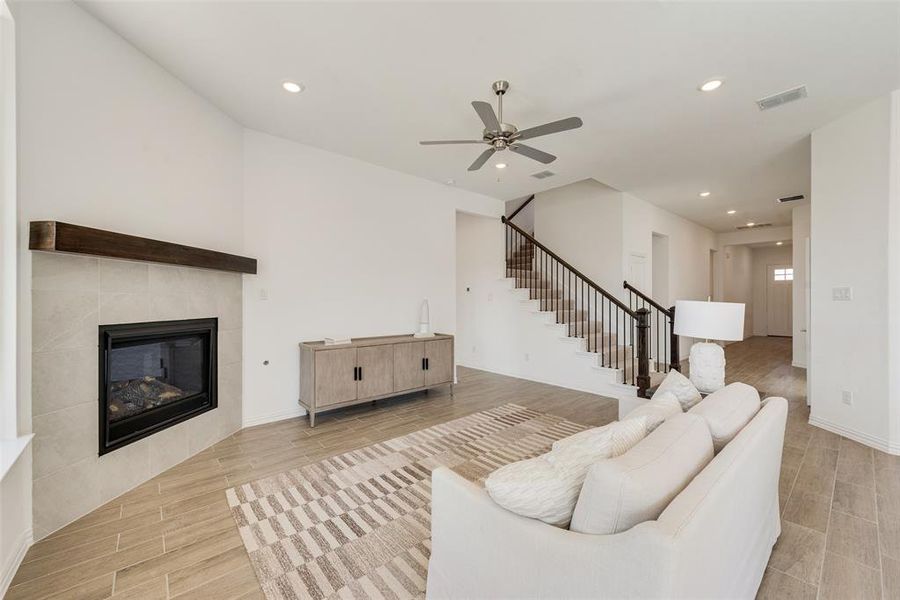 Living room featuring light hardwood / wood-style floors, a tiled fireplace, and ceiling fan