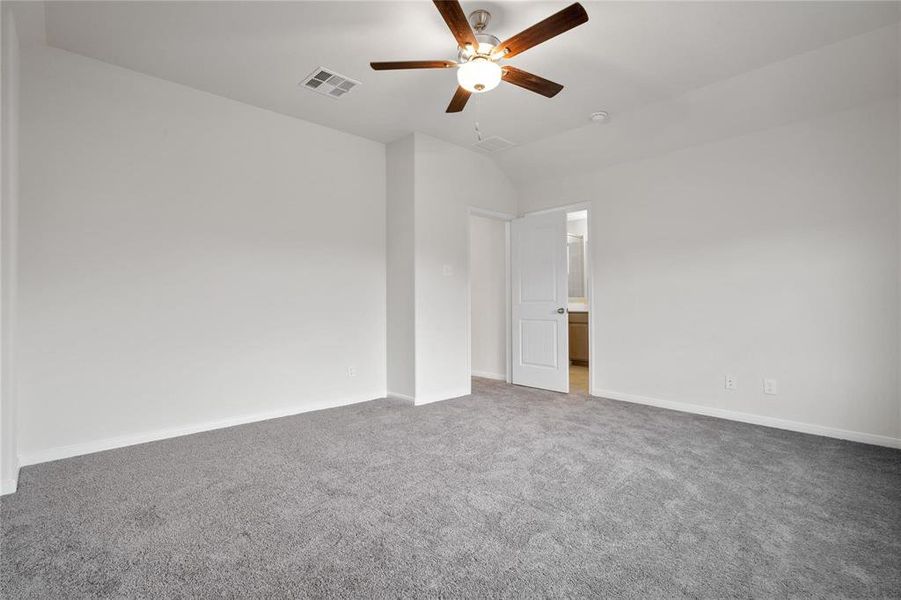 This primary bedroom offers a blank slate, ready for your imagination. Plush carpeting and neutral tones provide a comforting backdrop, while the ceiling fan ensures year-round comfort. **This image is from another Saratoga Home with similar floor plan and finishes, not the Brayden floorplan.**