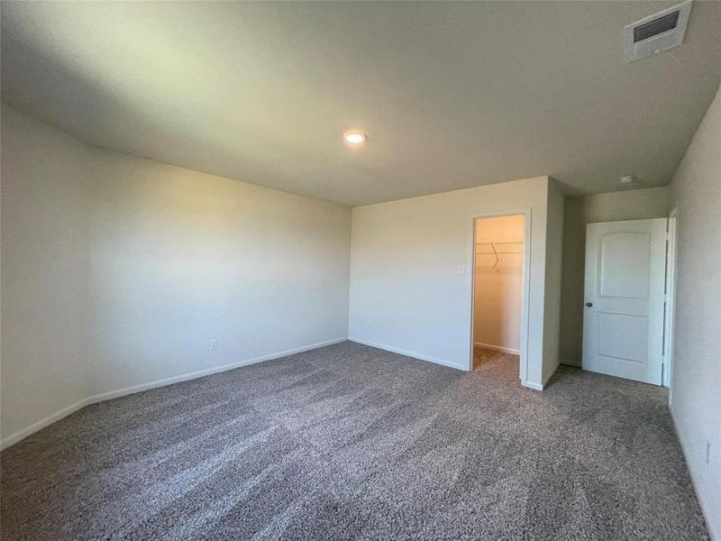 Unfurnished bedroom featuring dark carpet, a closet, and a spacious closet