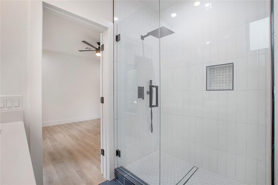 Bathroom featuring hardwood / wood-style floors, ceiling fan, and a shower with door