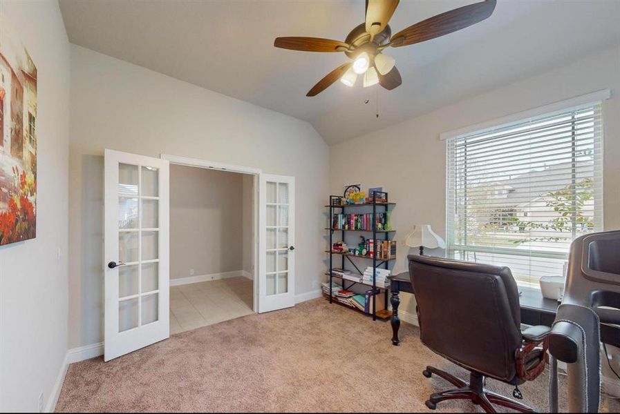 Carpeted office featuring french doors, ceiling fan, and vaulted ceiling