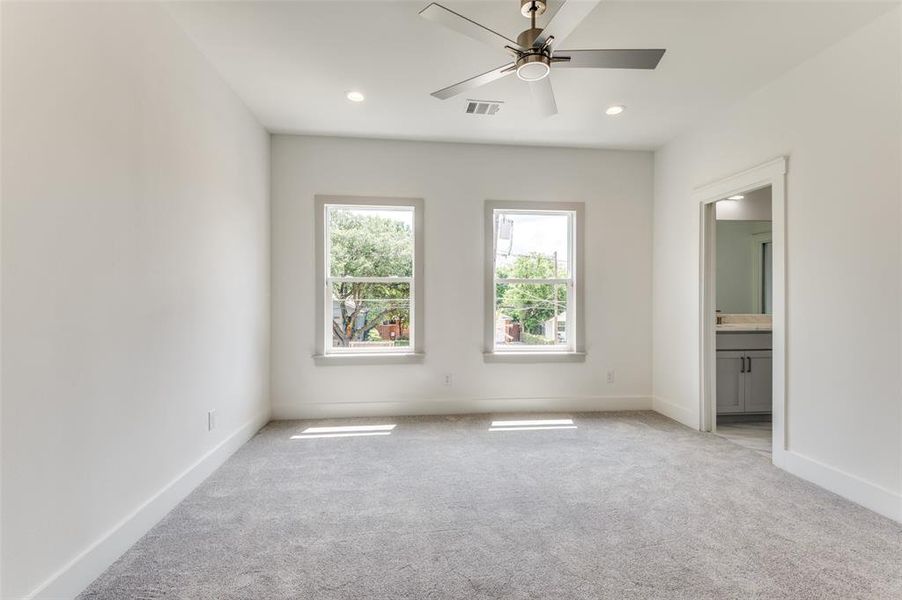 Unfurnished bedroom featuring light colored carpet, connected bathroom, and ceiling fan