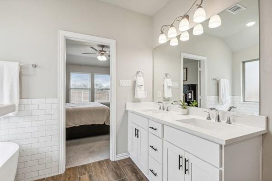 Bathroom with ceiling fan, double vanity, hardwood / wood-style floors, a washtub, and lofted ceiling